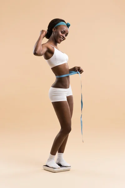 Woman standing on scale measuring waist with tape — Stock Photo, Image