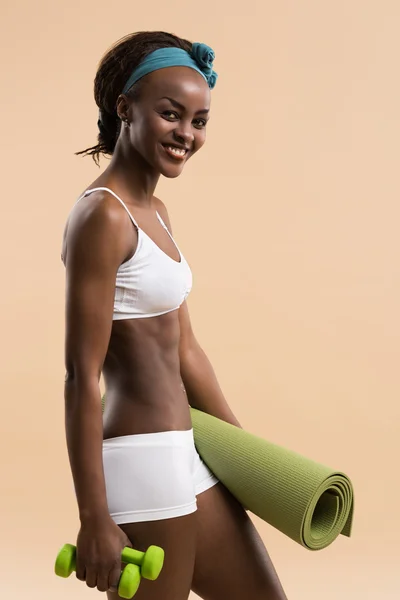 Женщина с гантелями и ковриком для йоги — стоковое фото