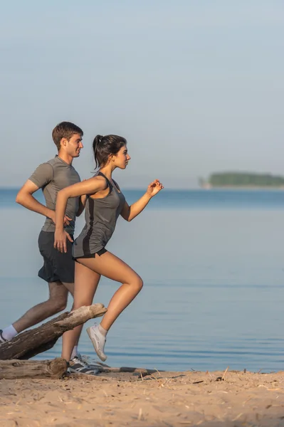 Lyckliga par jogging på stranden. — Stockfoto