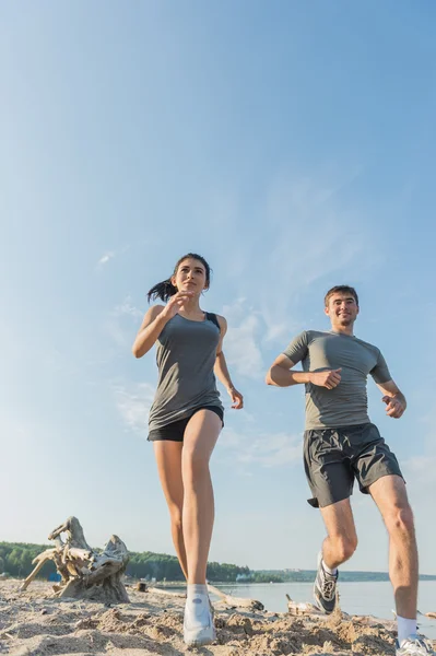 Gelukkige paar joggen op het strand. — Stockfoto