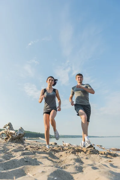 Lyckliga par jogging på stranden. — Stockfoto