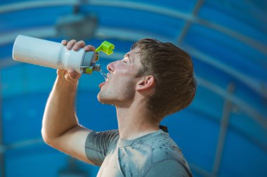 Athletic young man drinking water clipart