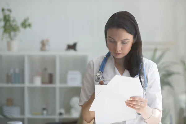 Médico usando telefone celular e segurando papéis — Fotografia de Stock