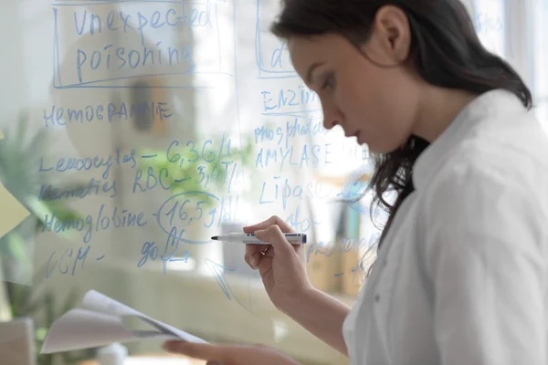 Doctor writing on transparent board — Stock Photo, Image