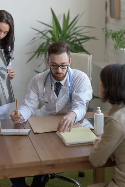 Läkaren håller xray och pratar med patienten — Stockfoto