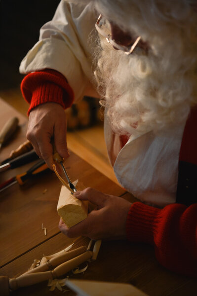 Santa carving something from wooden plank