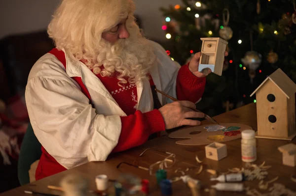 Santa Claus haciendo y pintando juguetes — Foto de Stock