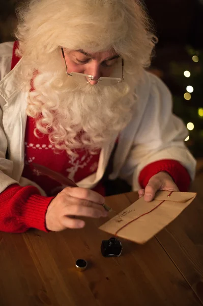 Санта-Клаус пишет и подписывает письмо — стоковое фото