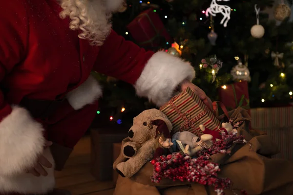 Santa poner regalos bajo el árbol de Navidad — Foto de Stock