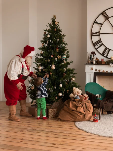 Weihnachtsmann mit Kind schmückt Weihnachtsbaum — Stockfoto