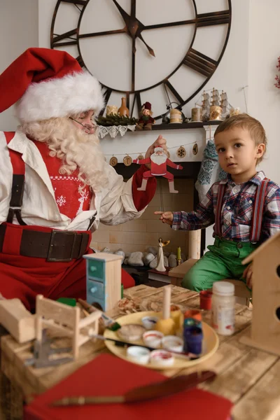 Papai Noel com criança fazendo brinquedos — Fotografia de Stock