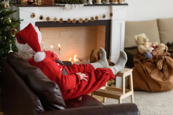 Weihnachtsmann wärmt sich am Kamin — Stockfoto