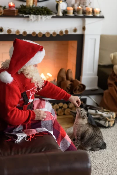 Weihnachtsmann füttert seine Katze — Stockfoto