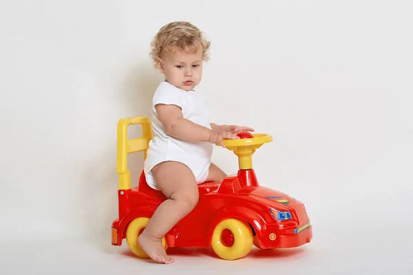 Χαριτωμένο Μικρό Αγόρι Ιππασία Κόκκινο Και Κίτρινο Αυτοκίνητο Παιχνίδι Κοιτάζοντας — Φωτογραφία Αρχείου