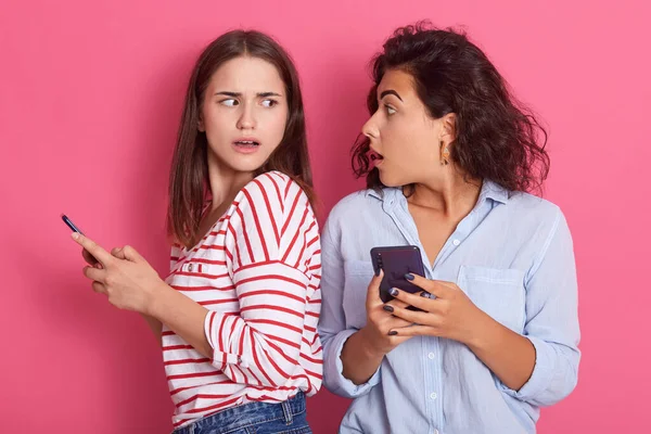 Megdöbbent Nők Nézik Egymást Miközben Mobiltelefonokat Tartanak Kezükben Csíkos Ingben — Stock Fotó