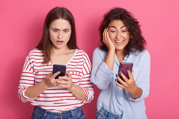 Két Fiatal Lány Különböző Érzelmek Segítségével Mobiltelefonok Pózol Elszigetelt Rózsa — Stock Fotó
