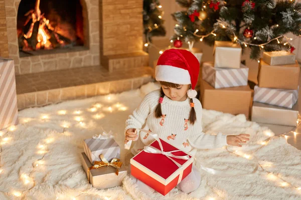 Schattig Klein Meisje Openen Kerstcadeau Thuis Terwijl Zitten Zacht Tapijt — Stockfoto