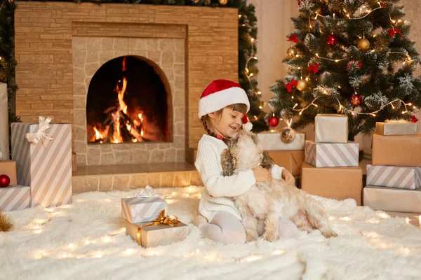 Šťastné Dítě Vánočním Klobouku Objímající Štěně Šaty Bílý Svetr Santa — Stock fotografie