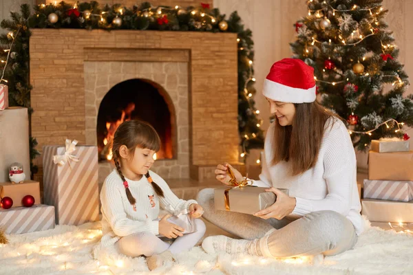 圣诞快乐 母亲和孩子们带着礼物在家里 双腿交叉坐在地板上 兴奋而快乐 在喜庆的客厅里微笑着看着他们的礼物 — 图库照片