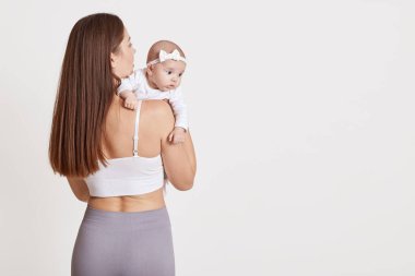 Anne ve yeni doğanın yan yana durduğu arka plan beyaz arka plan üzerinde izole edilmiş, tozluk giymiş kadın yan bakıyor, terfi ya da reklam için fotokopi odası.