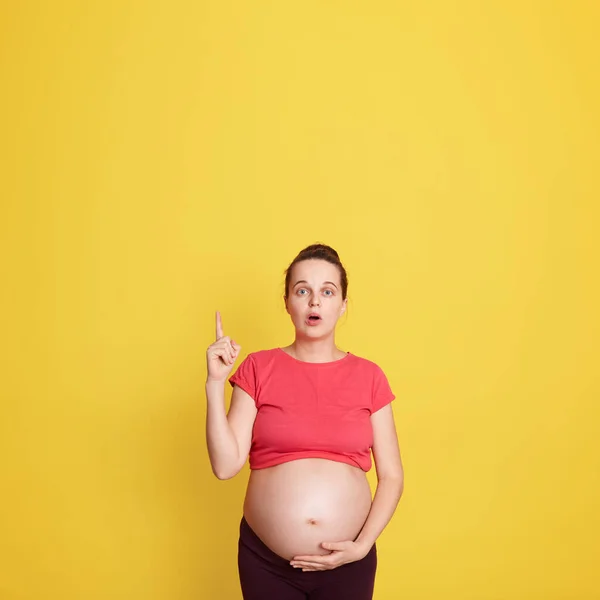 Удивлённая Беременная Женщина Показывающая Пальцем Жёлтый Фон Женщина Широко Раскрытым — стоковое фото