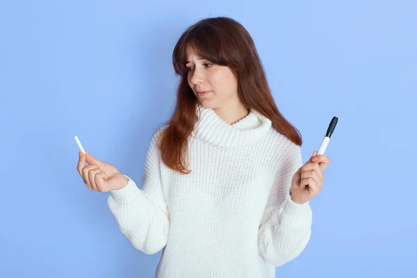 新的电子香烟 混合香烟在女性手中 深色头发的女孩拿着烟草加热系统隔离在蓝色背景 女士看着手杖 — 图库照片