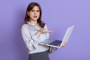 Bilgisayar işletim sorunları yüzünden hayal kırıklığına uğrayan genç Avrupalı kadın, kameraya şaşkın ve şaşkın bir ifadeyle bakıyor, beklenmedik sorunlar yaşıyor,.
