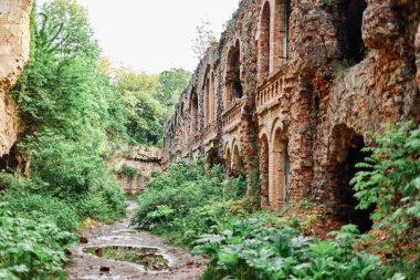 Bitkilerle kaplı antik harabeler, yağmurdan sonraki gün sessizlik, yoldaki su birikintileri, güzel bir manzara, yeşil çimenler ve çalılar, seyahat, turizm..