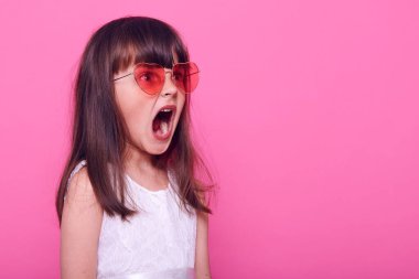 Koyu renk saçlı küçük bir kız korkunç bir şey görür, hissiz bir şekilde durur, yüzünü çevirir, yüzünde korku dolu çığlıklar atar, şık beyaz elbiseler giyer, pembe arka planda soyutlanır..