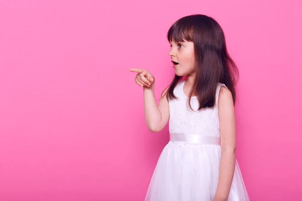 Niña Asombrada Vistiendo Elegante Vestido Blanco Mira Cámara Señalando Con —  Fotos de Stock