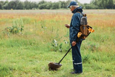 Meadow 'daki hazine avcısının profil portresi, metal dedektörüyle yer altında bulduğu madeni parayı tutan numismatist portresi..
