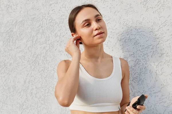Portrait Young Adult Woman Wearing White Sporty Top Standing Airpods — Stok Foto