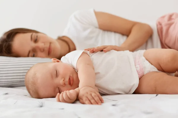 Indoor Shot Van Glimlachende Vrouw Liggend Met Slapende Meisje Dochter — Stockfoto