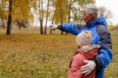 Yaşlı bir adam parktaki detaylara dikkat çekiyor. Etrafı renkli sonbahar yaprakları ve ağaçlarla çevrili genç bir kız öğrenme ve iletişim anlarını yakalıyor..