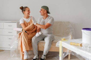 İki mutlu birey, yeni boyanmış bir odada, bir kanepede dinleniyor, resim aktiviteleri arasında şakalaşarak bir anı paylaşıyorlar. Çalışma alanları aletlerle dolu..