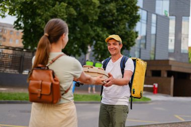 Bir insan, gün içinde şehir caddesinde bir müşteriye yemek siparişi verir. Her iki kişi de gülümsüyor ve takastan hoşlanıyor gibi görünüyor..