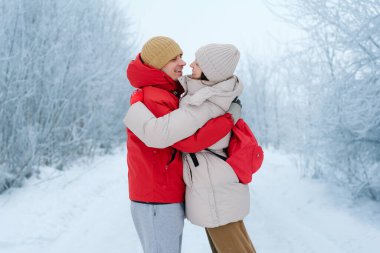 Karlı bir ormanda bir erkek ve bir kadın sıcak bir şekilde kucaklaşır. Kışlık palto ve şapka giyiyorlar. Çevrelerindeki ağaçlar buzla kaplıdır. Soğuk bir gün..