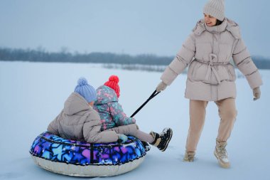 İki çocuk renkli bir metroda otururken bir yetişkin onları soğuk bir kış gününde karlı bir arazide sürüklüyor ve karda eğleniyor..
