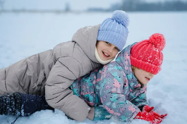 İki çocuk karda kış gününün tadını çıkarıyor. Sıkı ceketler ve şapkalar giyip birlikte oynuyorlar, gülüyorlar ve eğleniyorlar..
