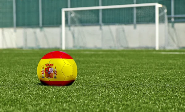 Balón de fútbol en el campo verde- bandera de España — Foto de Stock