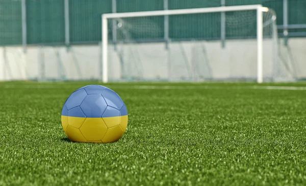 Fotbalový míč na zelené pole vlajka Ukrajiny — Stock fotografie
