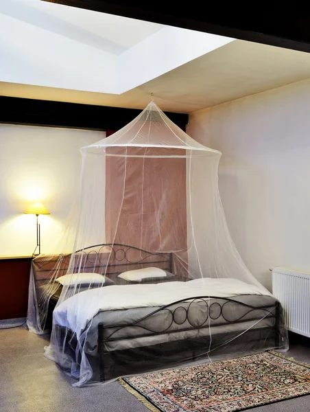 Cosi vintage seng med myggenet i en restaureret hems - Stock-foto