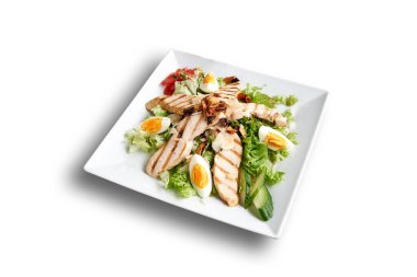 Beyaz tabakta Sezar salatası var. Kırpılmış beyaz bir tabakta.