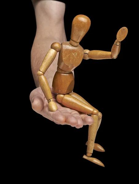 Wooden dummy say hello and is sItting on a helping hand — Stock Photo, Image