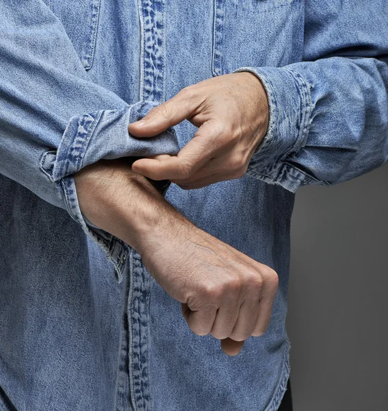 Мужчина в джинсовой рубашке закатывает рукава — стоковое фото