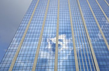 Skyscraper reflecting clouds in the sky clipart