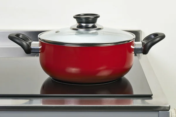 Κόκκινο κεραμικό τηγάνι με κάλυμμα στην εστία μαγειρέματος — Φωτογραφία Αρχείου