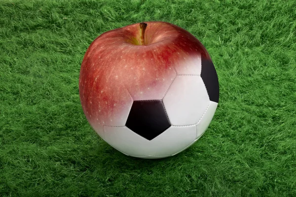 Soccer ball on green grass to apple — Stock Photo, Image