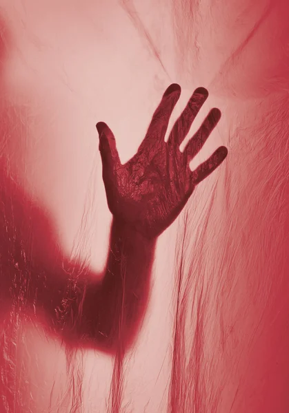 Silhouette of a hand behind red transparent plastic — Stock Photo, Image