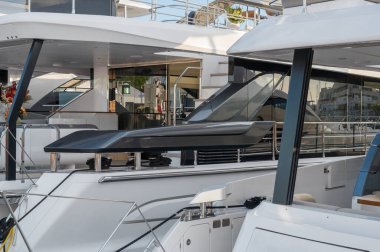 Tertemiz hatları ve modern tasarımı olan, parlak gri ve beyaz bir yat, Limasol Marina 'daki cam pencerelerinde öğleden sonra ışığını ve metalik donanımı yansıtıyor.